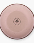 The bottom of a dusty rose rolled enamel bowl on a white background