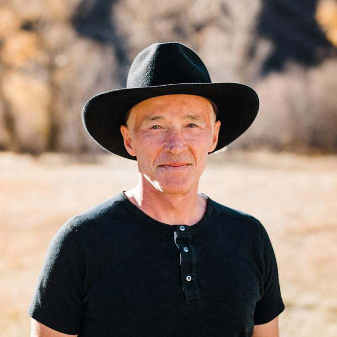 Man wearing a black hat and black shirt in a desert-like setting